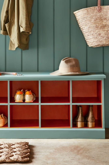 Paneled mudroom painted in green shade, Pleat, with contrasting deep red (Heat) shelving.