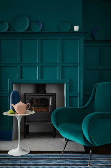 Living space featuring walls and paneling painted in dark green (Mid Azure Green), a matching velvet sofa and a stripy rug.