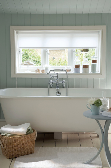 Paneled bathroom painted in light green (Salix) with a white bathtub under a large window.