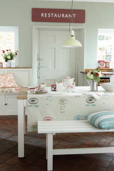 Kitchen diner with walls painted in the grey-green shade 'Pearl Colour', alongside a wooden table with a white bench.