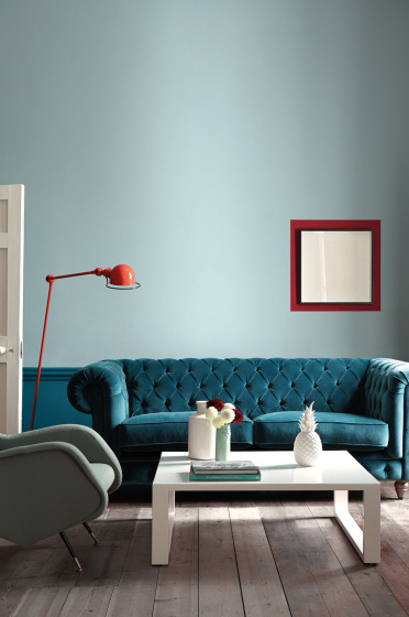 Living space with the wall painted in muted blue shade 'Celestial Blue' with a teal sofa and white coffee table.