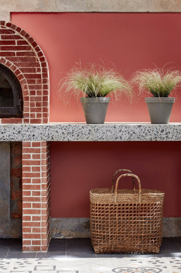 Outdoor kitchen painted in deep terracotta red 'Tuscan Red' with brickwork, plants and a basket.
