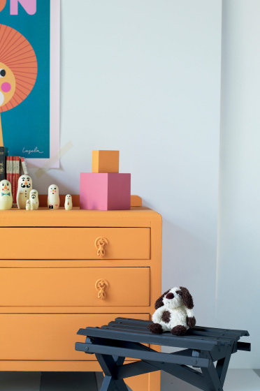Nursery featuring bright orange drawers (Marigold) and cartoon lion artwork on contrasting grey walls (Bone China Blue).