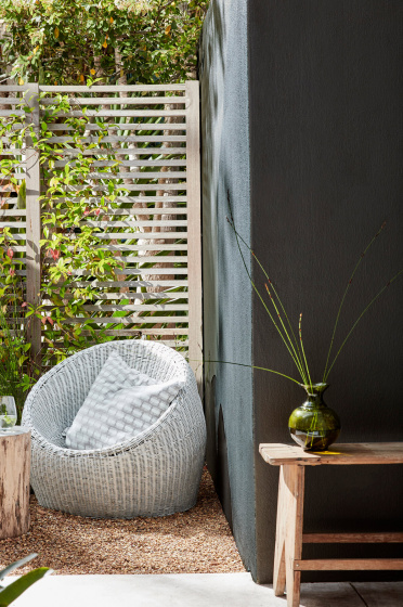 Garden with a bean bag chair placed next to a dark off-black wall painted in 'Obsidian Green' and in front of a wooden fence.