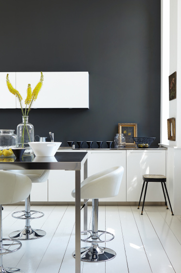 Rich black (Lamp Black) kitchen with bright white units and stools next to a black table.