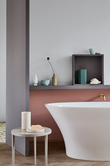 A bathtub in front of a wall with the lower half in a muted pink (Blush) and the upper wall in grey (Gauze - Dark).
