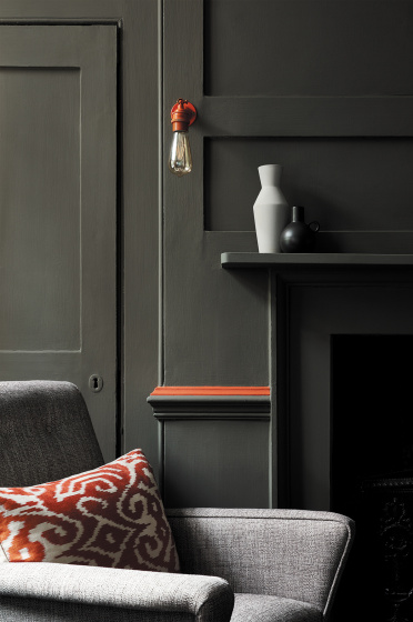 Living room color drenched in grey/ green shade 'Pompeian Ash' with a deep red contrast stripe and a grey sofa.