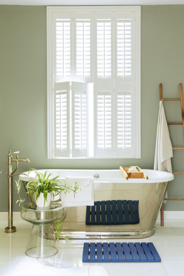 Bathroom painted in grey/ green 'Boringdon Green' with a silver bathtub under a large window.