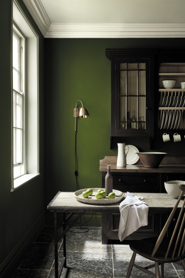 Dining area in deep green shade 'Jewel Beetle' with a wooden table and a rich brown 'Chocolate Colour' dresser. 