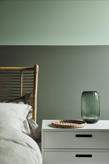 Close up of bedroom with the upper wall painted in Aquamarine and the lower wall in Aquamarine - Pale with a side table.