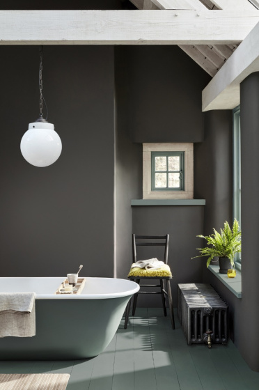 Bathroom painted in dark grey 'Vulcan' with contrasting grey, green (Livid) details with a bathtub, chair and window.