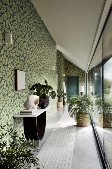 Long hallway with two tone blue and green wallpaper (Beech Nut - Florence) with a big window and plants.