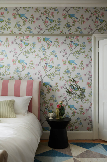 Bedroom featuring grey floral and bird wallpaper (Aderyn - French Grey) with a pink striped bed and sidetable.