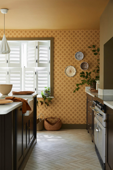 Kitchen space featuring golden yellow small print floral wallpaper (Ditsy Block - Bombolone) with a large window and dark brown cabinets.