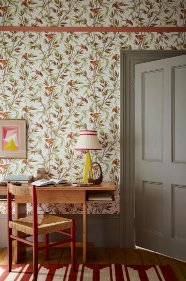 Home study space featuring bird and leaf wallpaper (Great Ormond St - Galette) with a grey door, wooden desk and chair.