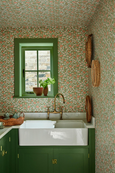 Pantry with the green and pink small print ditsy floral wallpaper 'Spring Flowers - Garden' on the walls and ceiling with dark green woodwork and a window above a sink.