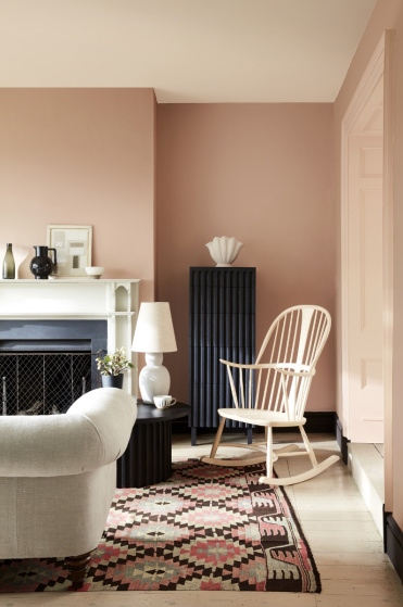 Pale pink living room in varying shades of Masquerade, alongside a rocking chair, sofa and Aztec rug.